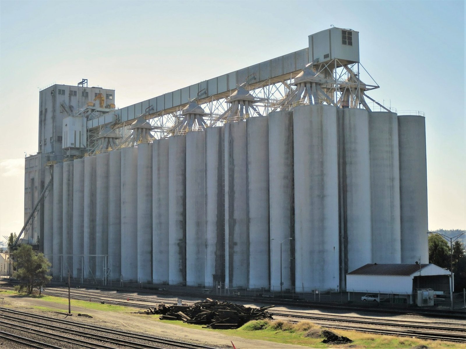 A long white concrete elevator with a gallery along the top, beside railroad tracks