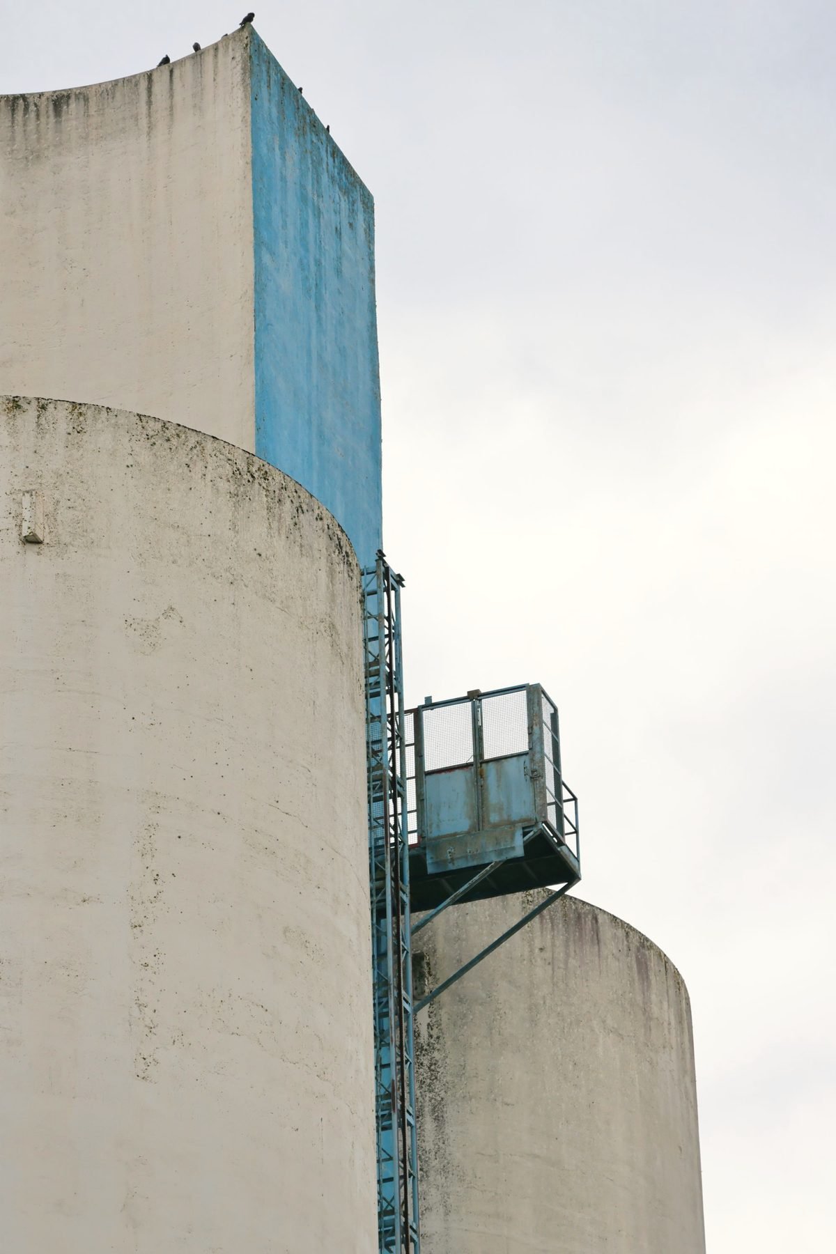 Close view of a tall concrete silo with a steel ladder and platform