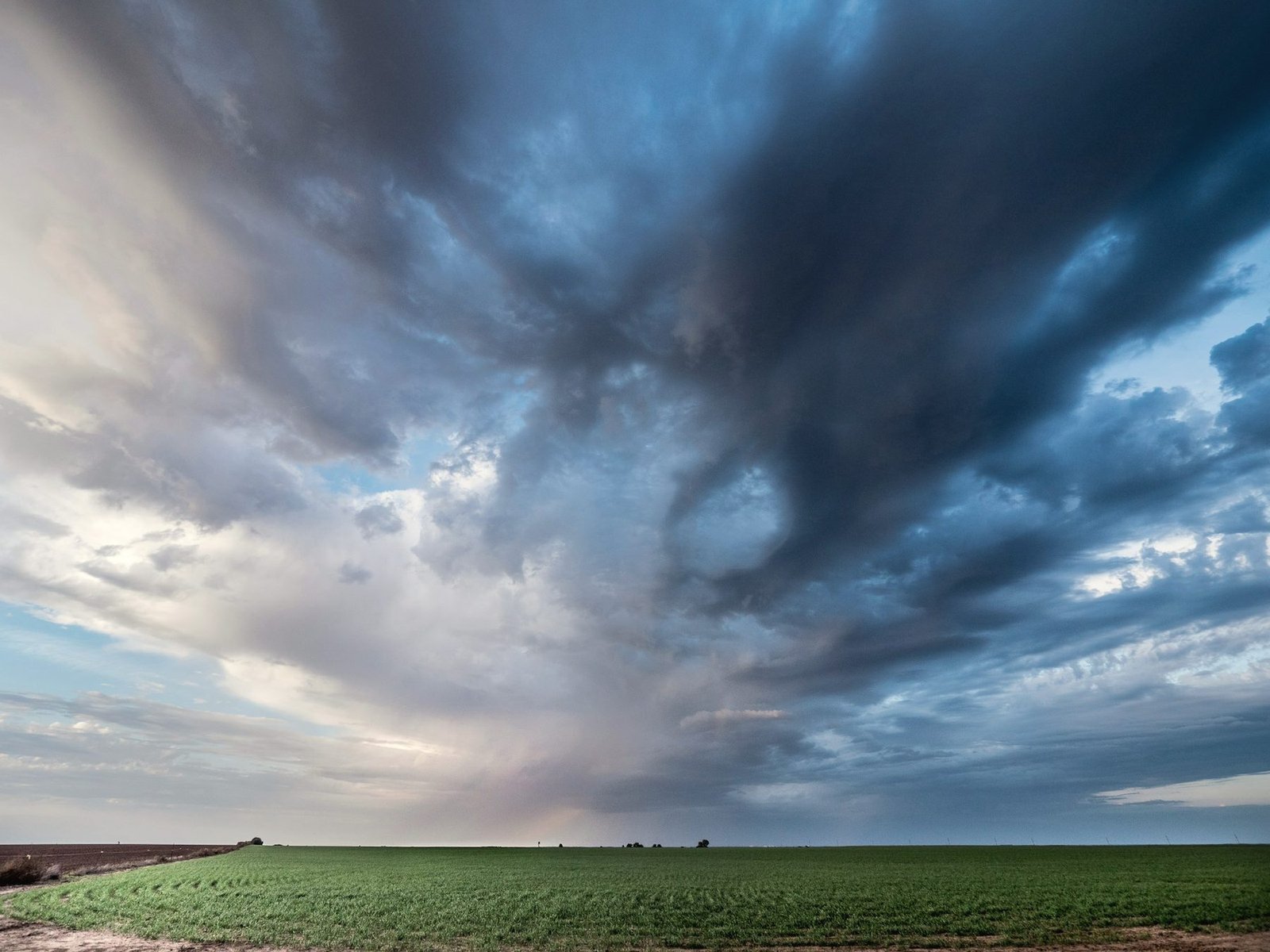 Storm clouds building over a flat green field